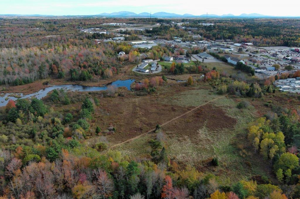 Aerial image of a forest, field and part of High Street with Mount Desert Island Mountains in the background horizon
